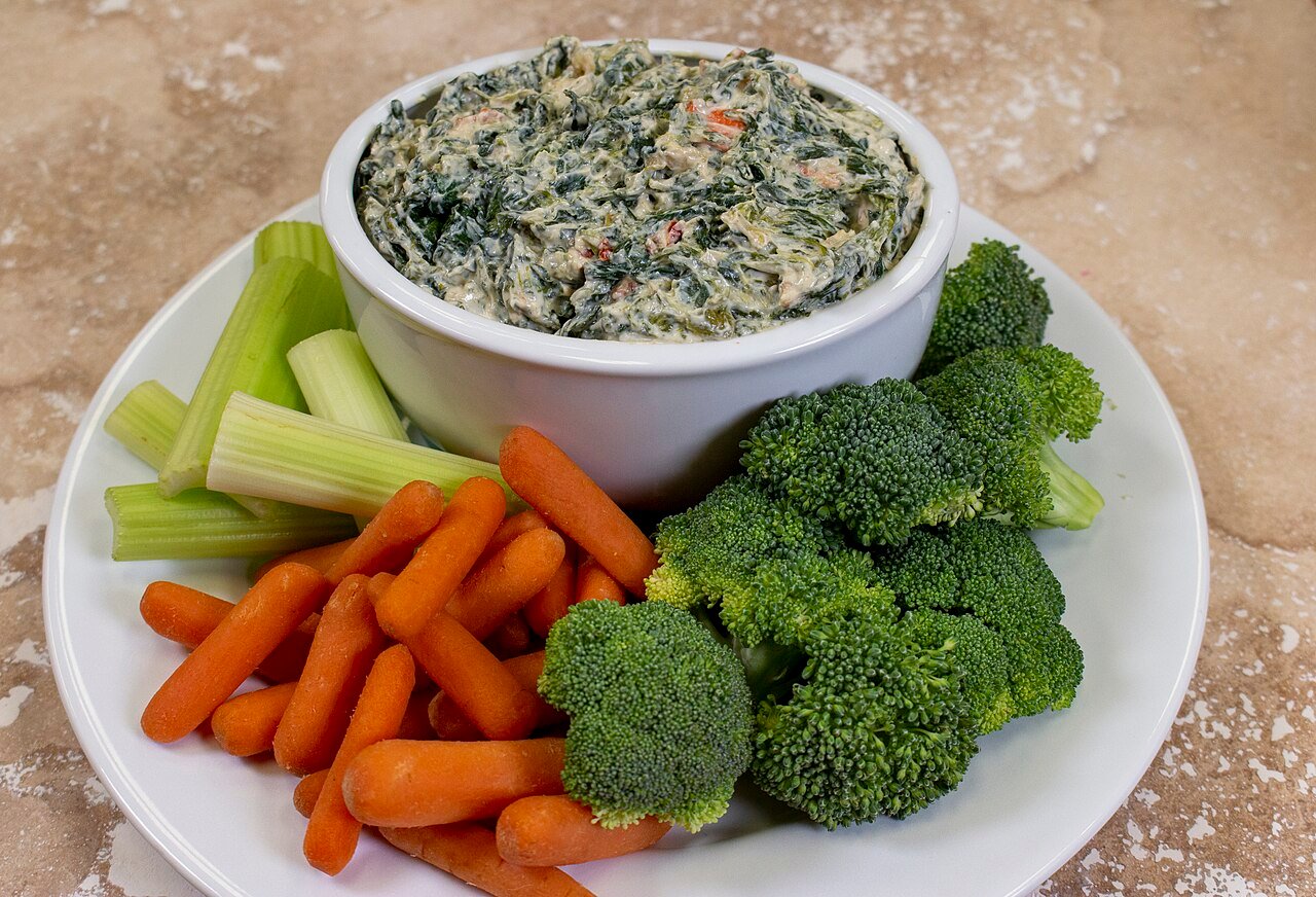 Creamy spinach dip served with fresh raw vegetables, a keto party appetizer spread
