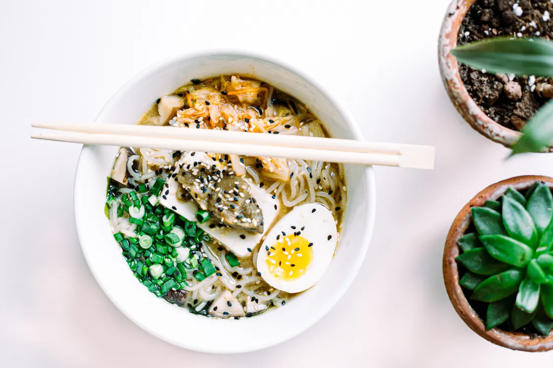 Bowl of translucent shirataki-style noodles with soft egg, greens, and chopsticks