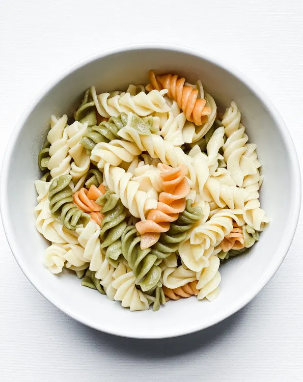 Fresh pasta salad with colorful vegetables in a white bowl